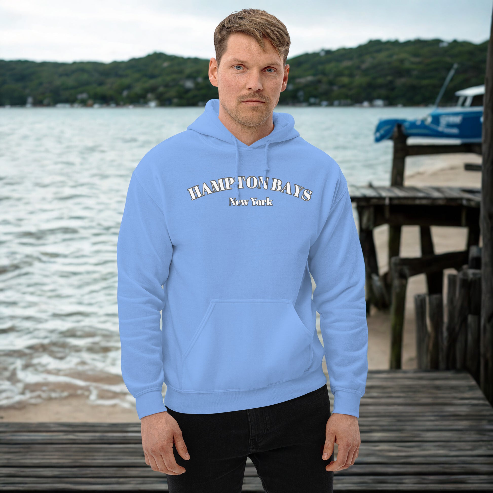 Light blue Hampton Bays Hoodie worn by man near water, cozy unisex sweatshirt for seaside strolls and beach town style.